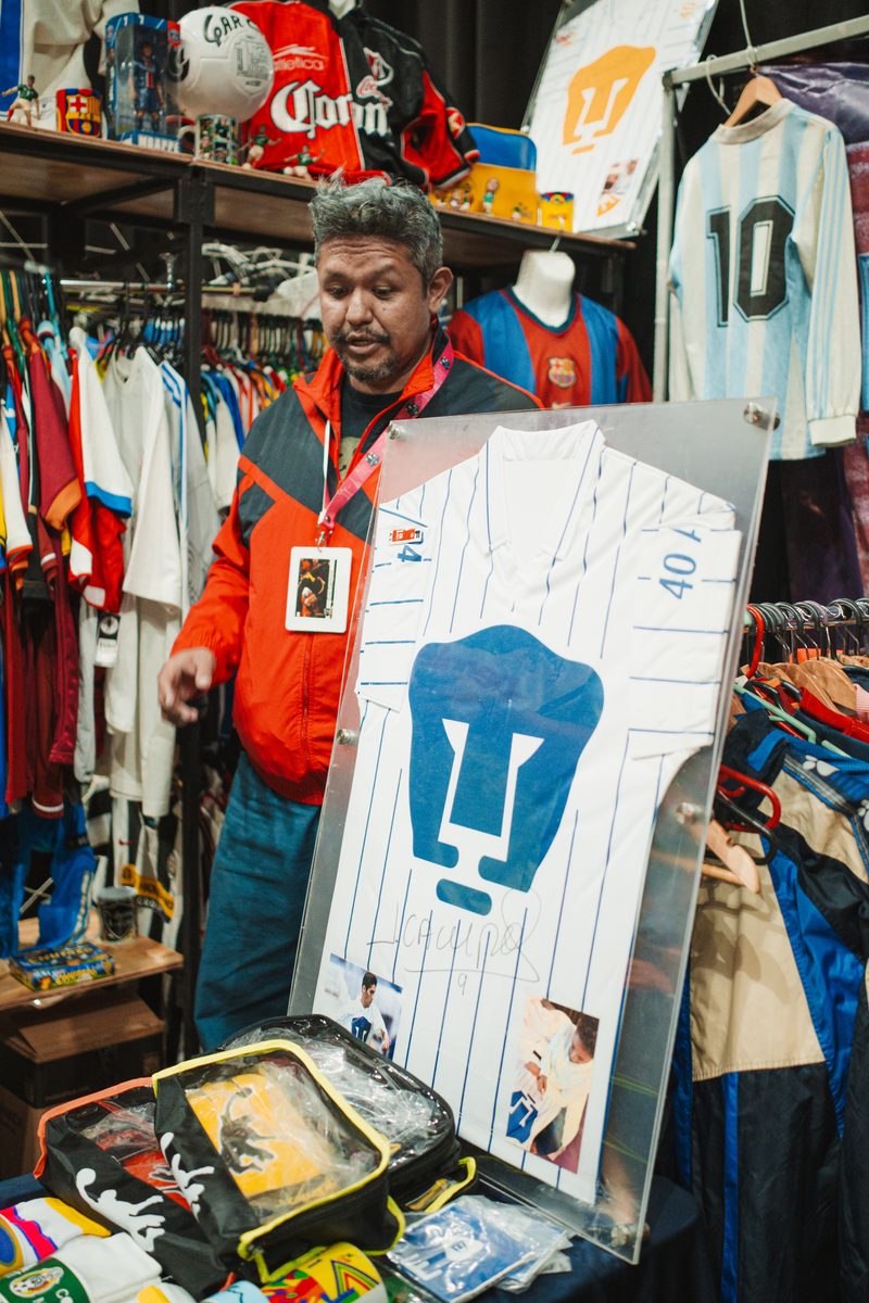 Vendedor mostrando jersey de Pumas firmado en marco