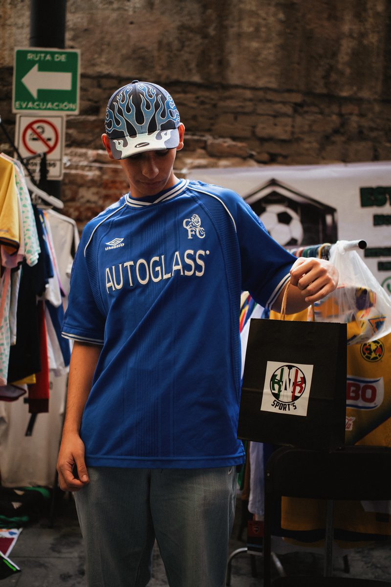 Asistente con jersey Chelsea Autoglass y bolsa de compras